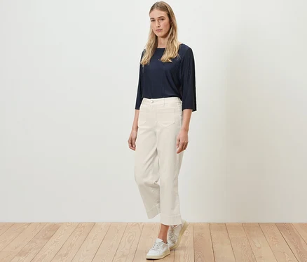 Une femme debout sur un plancher en bois porte un haut bleu marine et un jean évasé crème – Coupe «

Cara

».