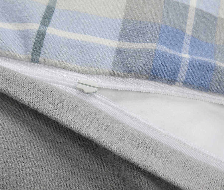 Gros plan sur une parure de lit en coton épais pour enfant de taille normale, avec un motif à carreaux et une fermeture éclair.