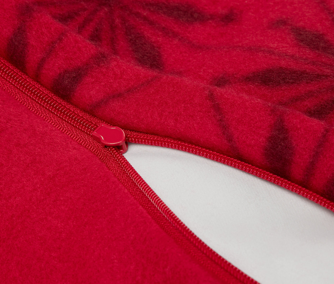 Gros plan d'une housse de coussin rouge avec fermeture éclair et motif floral foncé.