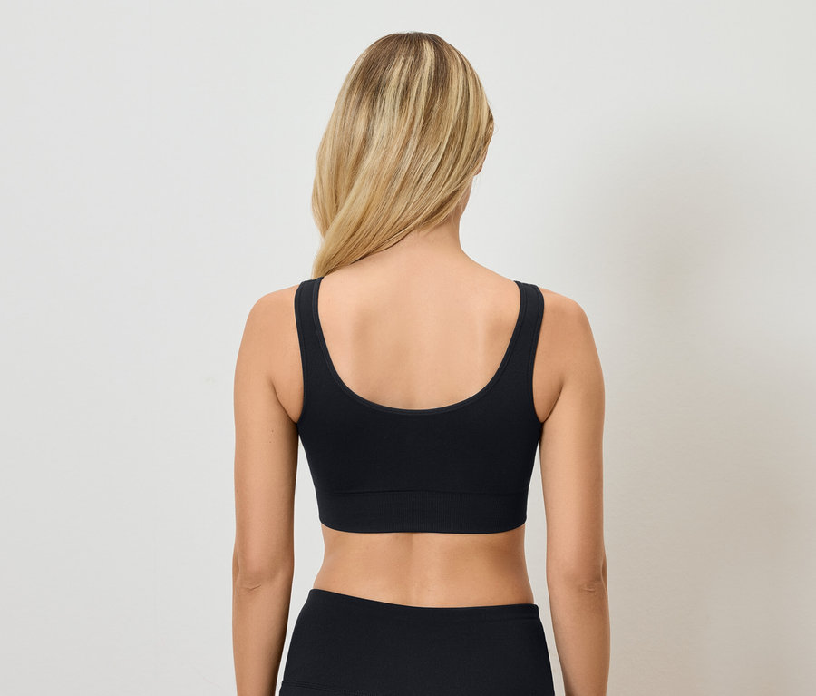 Vue arrière d'une femme blonde portant un soutien-gorge de sport et un pantalon noirs.