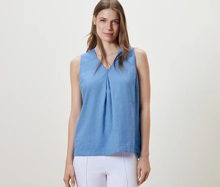Femme portant un chemisier sans manches en lin bleu clair.