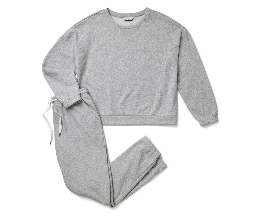 Un sweat-shirt et un pantalon de survêtement gris sont posés sur un fond blanc.