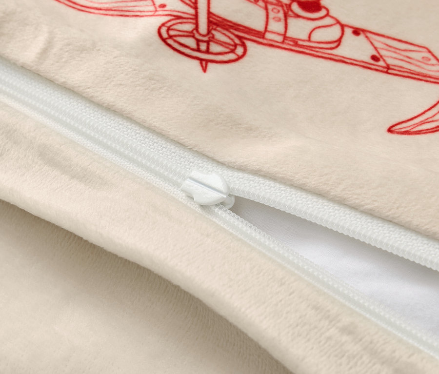 Housse de coussin beige avec une illustration rouge d'un skieur et une fermeture éclair blanche.