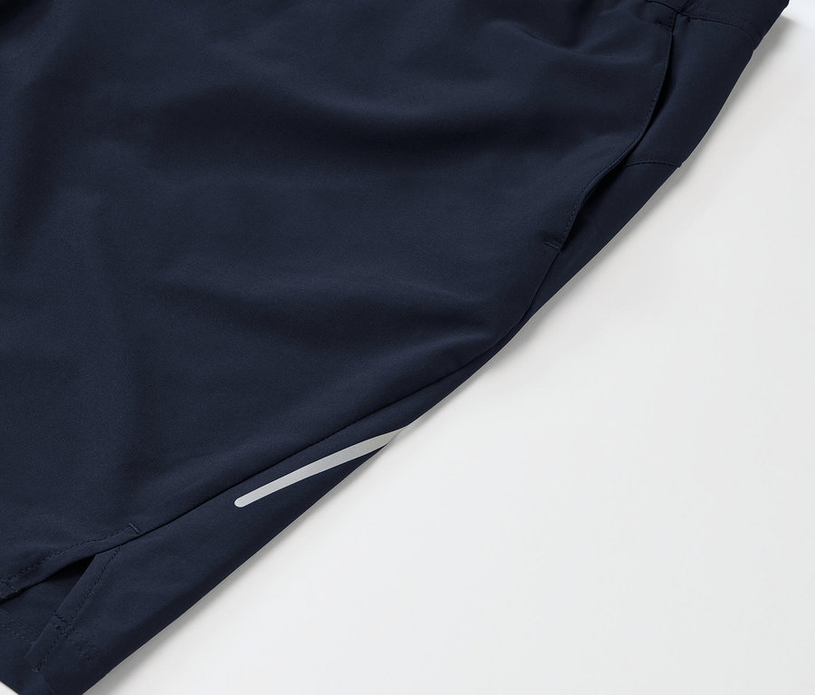 Détail d'un short de sport bleu marine avec une poche et un détail réfléchissant sur la jambe.