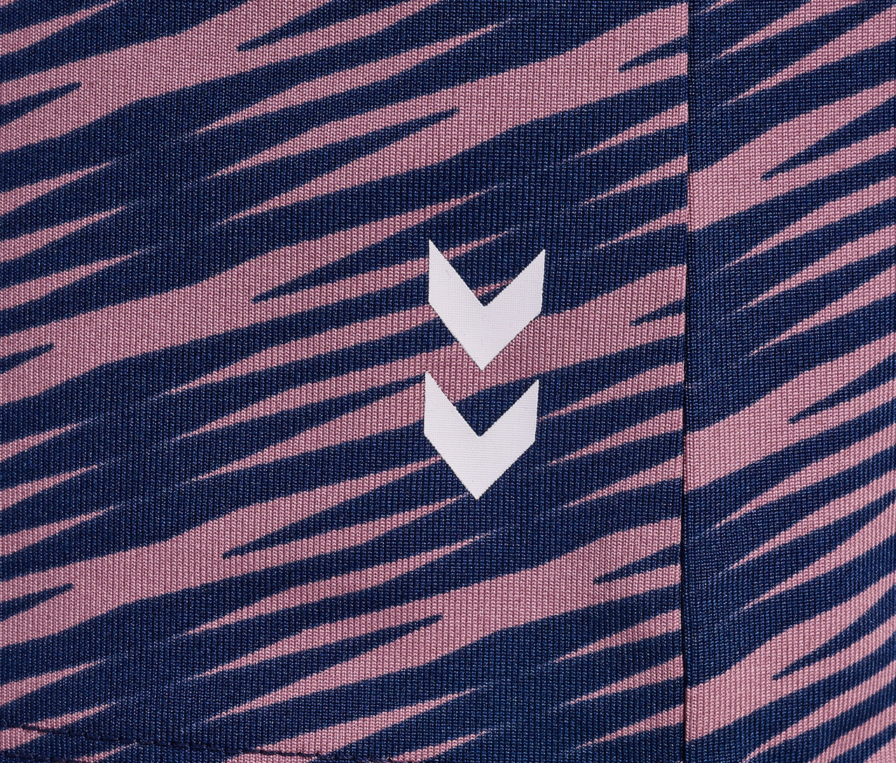 Gros plan sur le motif d'un t-shirt HUMMEL HMLJR Mix S/S, avec des rayures bleu foncé et roses et un logo.