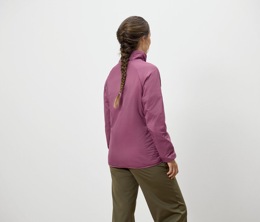 Femme avec une tresse, de dos, portant une veste rose et un pantalon vert.