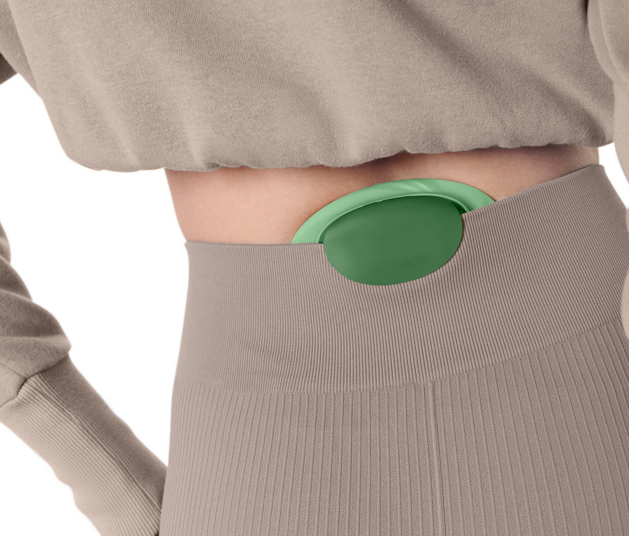 Une femme a une balle de massage verte insérée dans son pantalon.