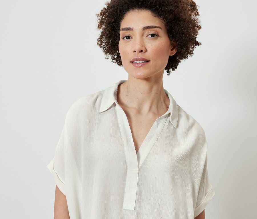 Portrait d'une femme aux cheveux bouclés bruns portant une blouse crème.