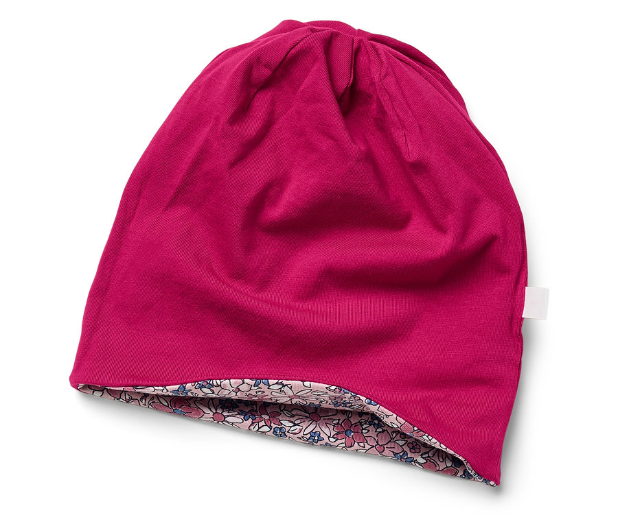 Un bonnet rose avec une doublure à fleurs posé sur un fond blanc.