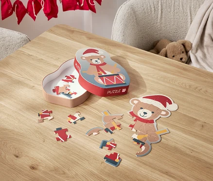 Un puzzle d'ours avec un bonnet de Noël est étalé sur une table, à côté de sa boîte.