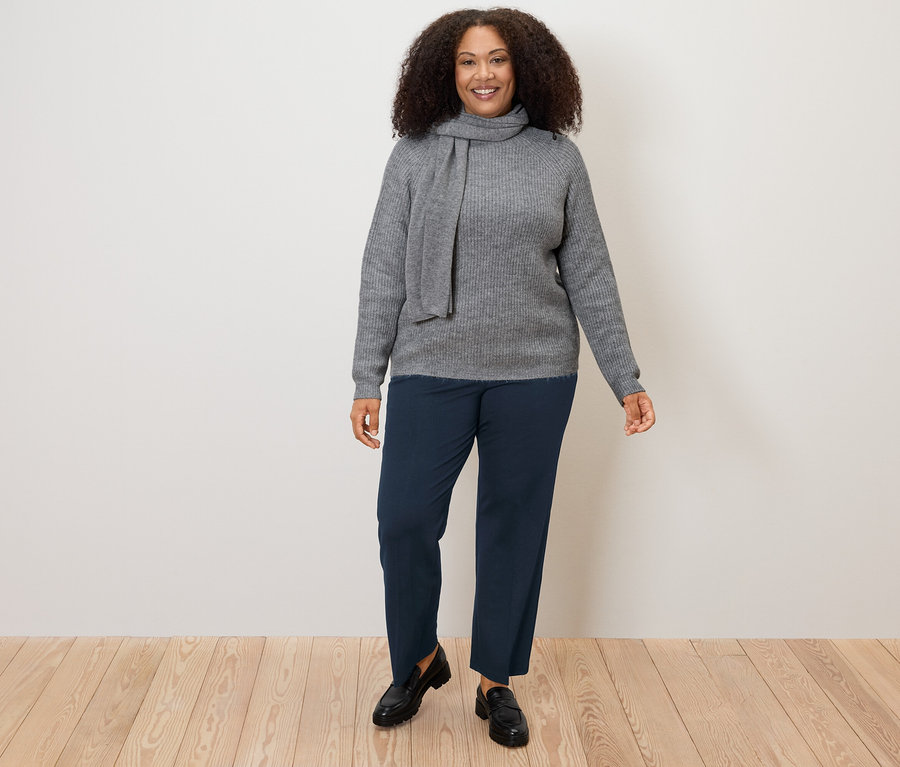 Femme portant un pull gris et un pantalon en jersey confort bleu marine.
