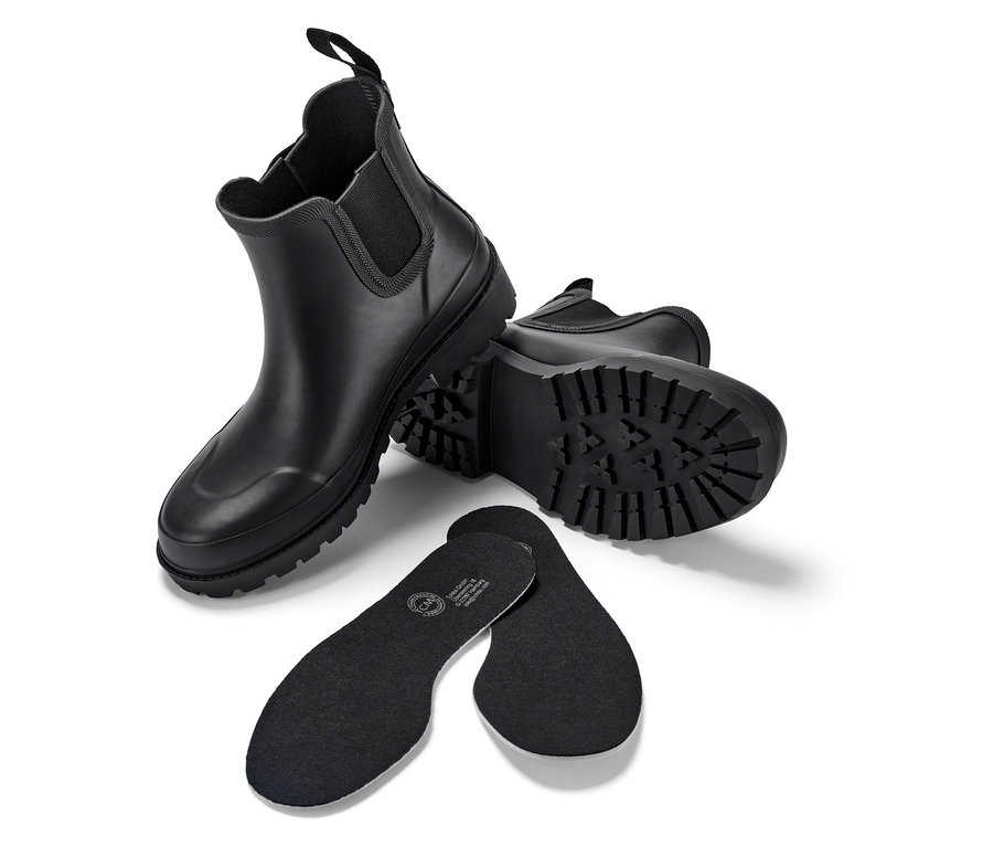 Deux bottes noires et deux semelles intérieures noires sur un fond blanc.