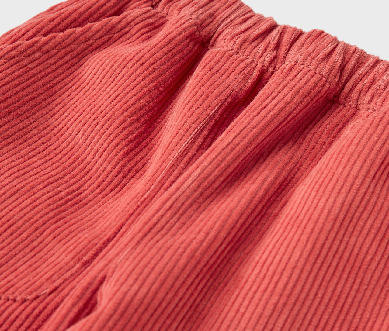 Détail d'un pantalon en velours rouge pour enfant à enfiler.