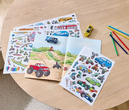 Sur une table, un livre d'autocollants «
Voitures
» ouvert et des crayons de couleur.
