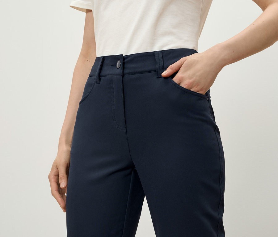 Une femme a la main dans la poche d'un pantalon bleu marine.