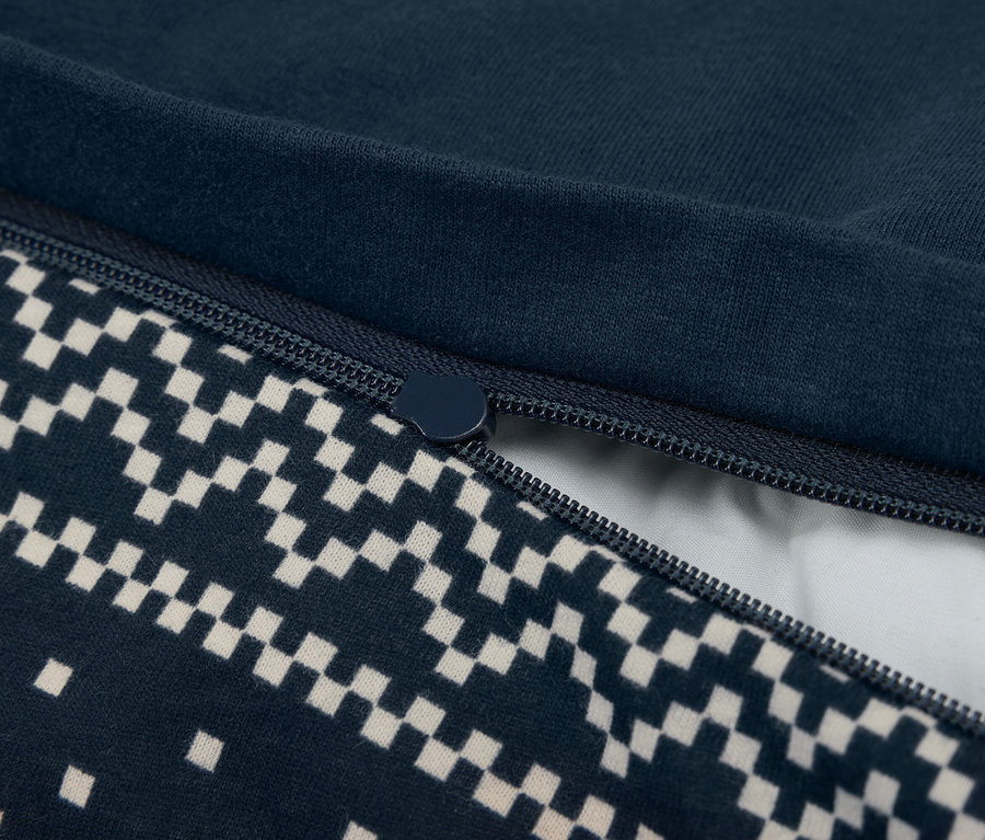 Gros plan d'une housse de couette bleu marine partiellement ouverte avec fermeture éclair et motif en damier.