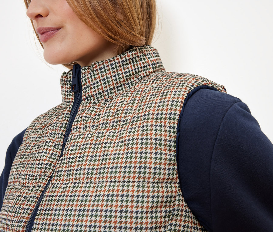 Détail d'un gilet matelassé pour femme à motif pied-de-poule avec des manches bleues.