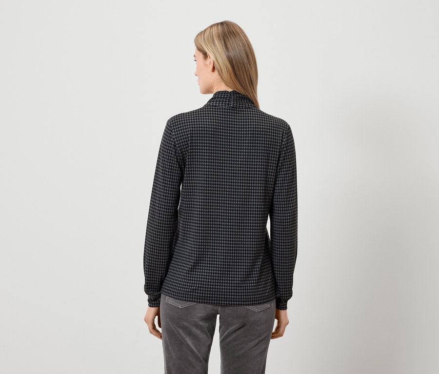 Vue arrière d'une femme portant un haut à manches longues gris et noir et un pantalon gris.