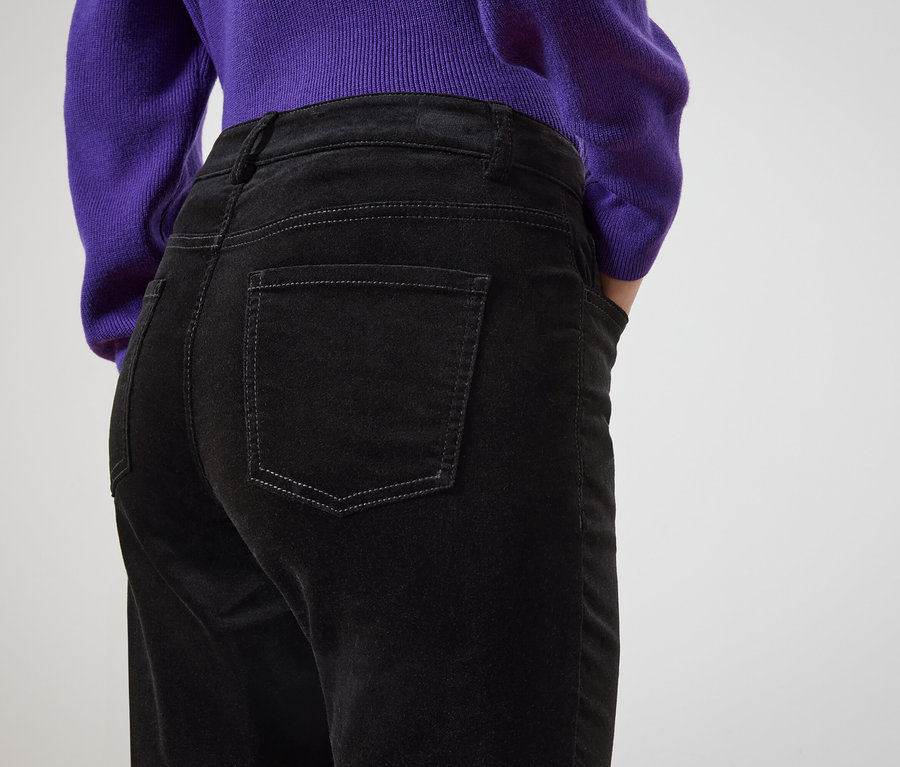 Vue de dos, une femme portant un jean noir et un pull violet.