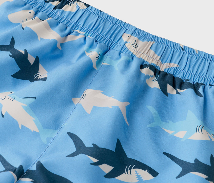 Gros plan d'un short de bain avec un motif de requins bleu clair et une ceinture élastique.
