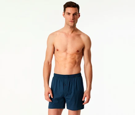 Un homme torse nu porte un 2 boxers SCHIESSER bleus sur fond blanc.