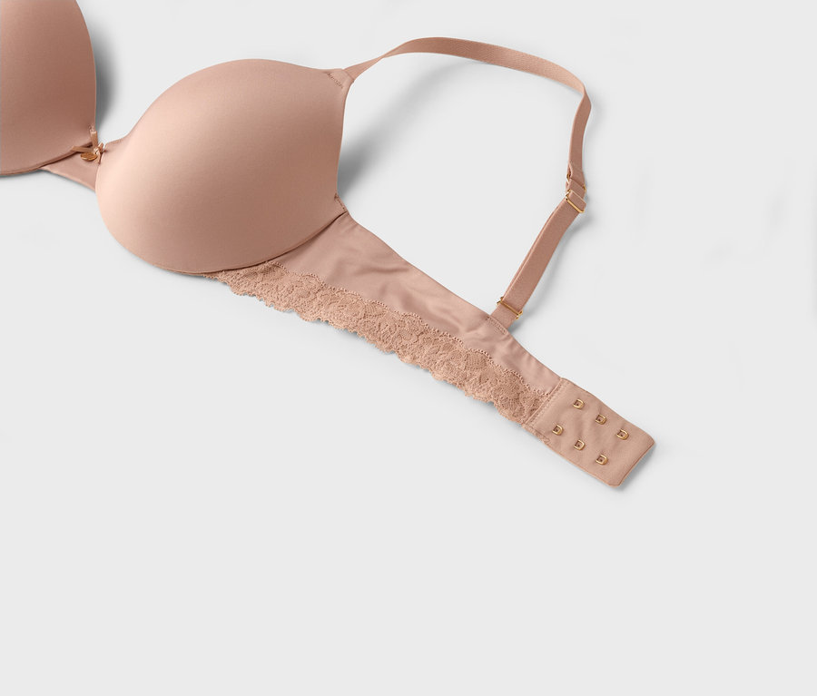Gros plan d'un soutien-gorge beige avec de la dentelle et des bretelles réglables.