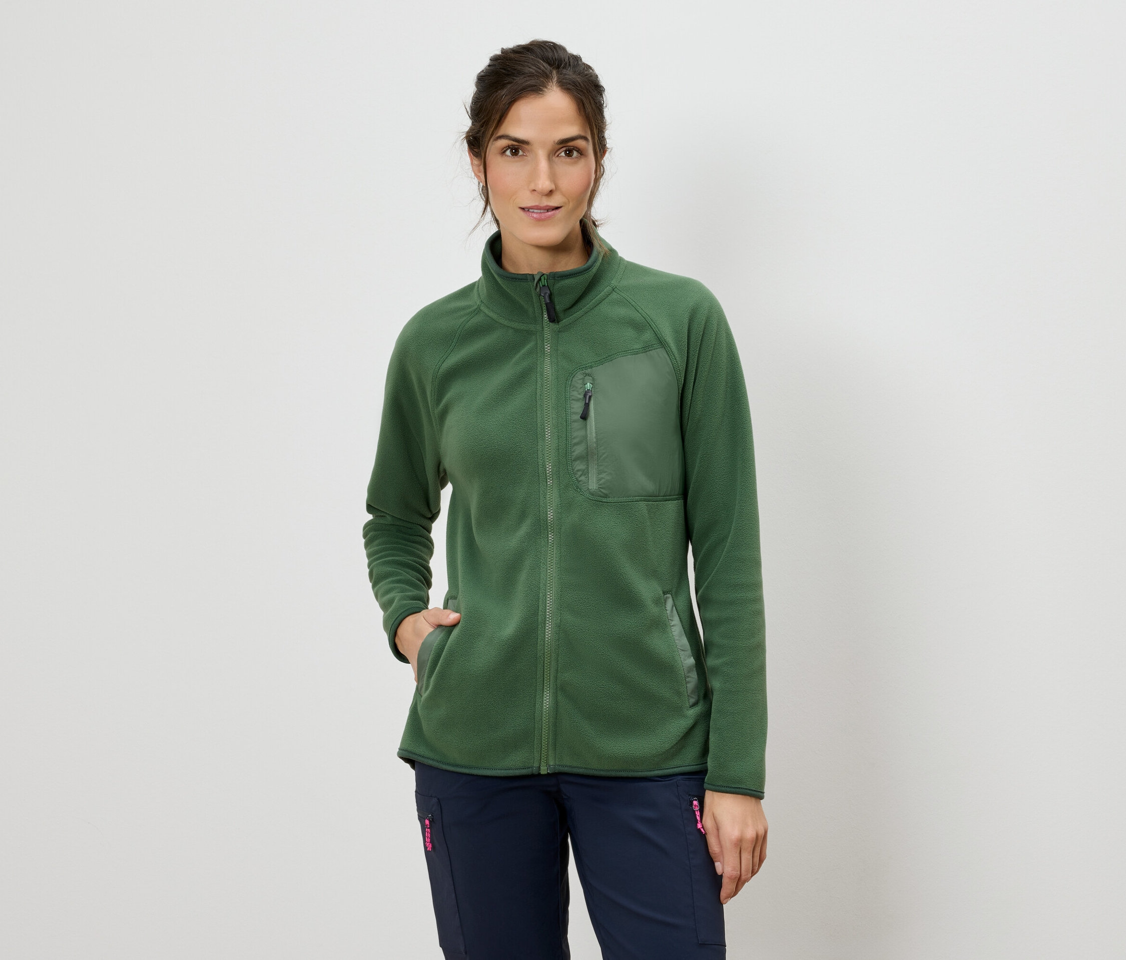 Femme portant une veste polaire verte zippée et un pantalon bleu.