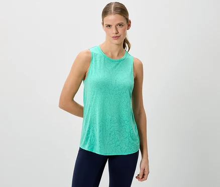Une femme porte un débardeur vert et un legging bleu sur un fond blanc.