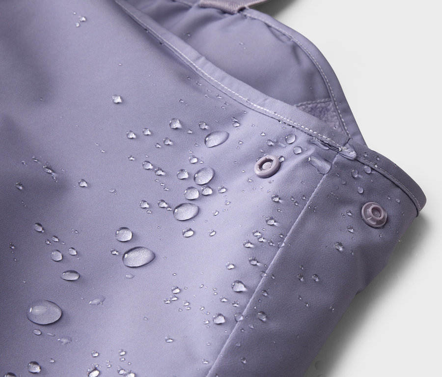 Gros plan d'un tissu violet avec des boutons-pression et des gouttes d'eau.