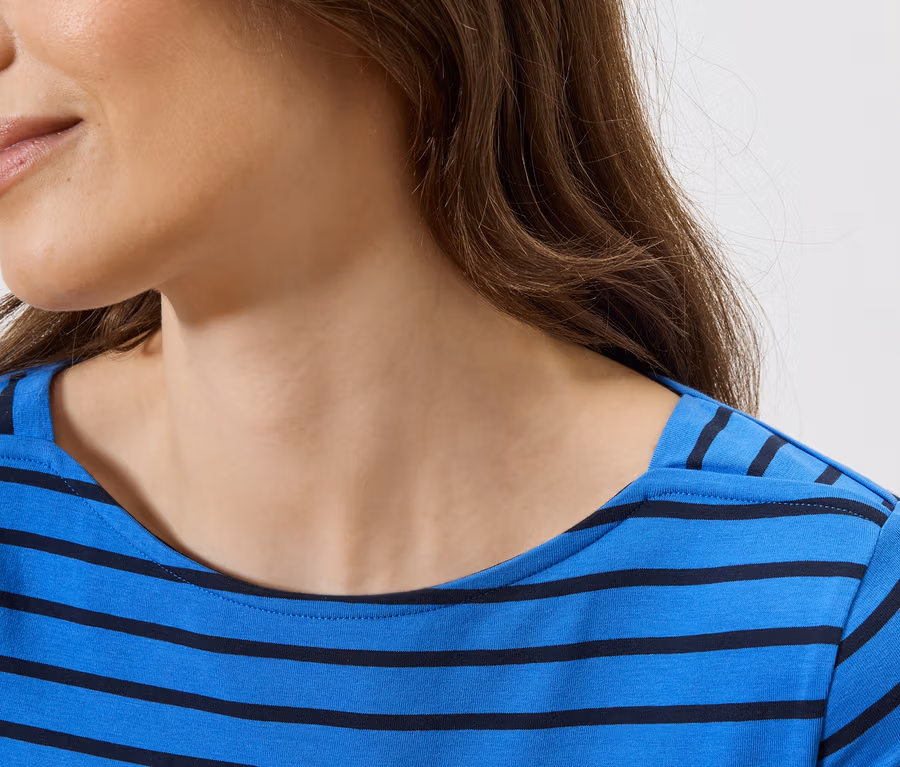 Gros plan d'une femme aux cheveux bruns portant un haut rayé bleu et noir.