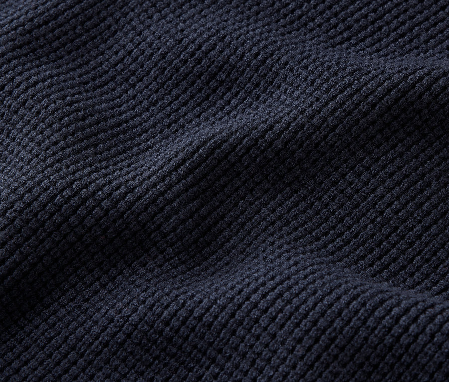 Gros plan sur un tissu de velours côtelé bleu foncé avec des plis.