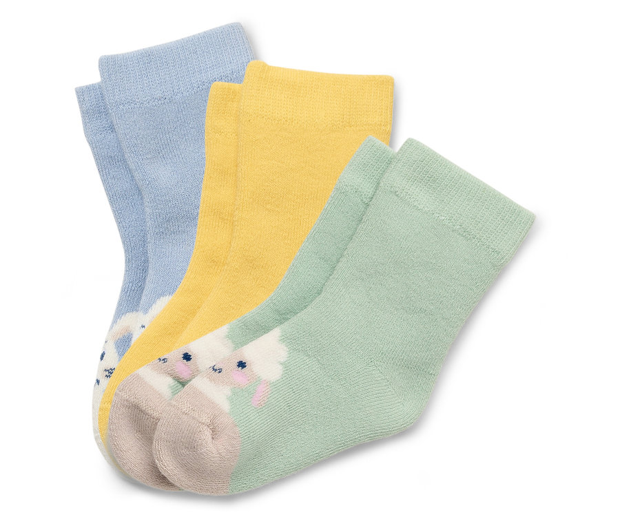 Trois chaussettes en bleu, jaune et vert avec des motifs de moutons sont posées les unes sur les autres.