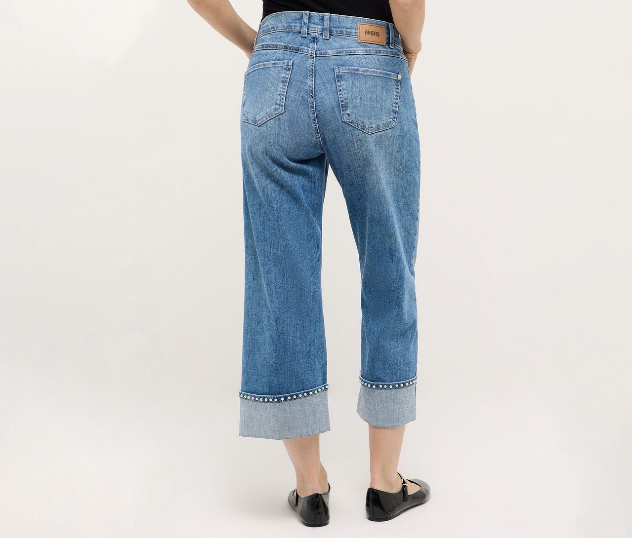 Personne vue de dos portant un jean Angels Denim « Linn Cool » associé à des chaussures noires sur un fond neutre.