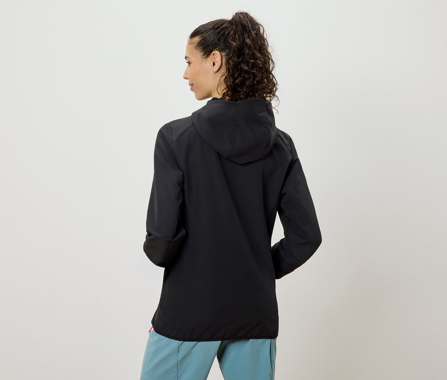 Vue arrière d'une femme portant une queue de cheval, une veste à capuche noire et un pantalon bleu clair.