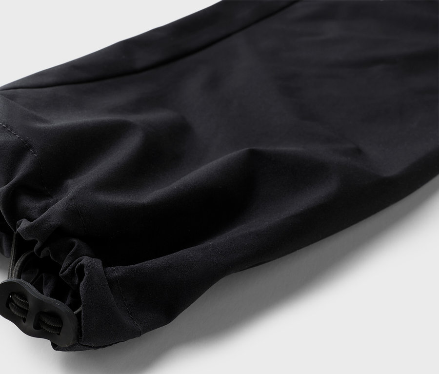 Gros plan sur le bas d'un pantalon noir avec un ourlet élastique et un cordon de serrage.