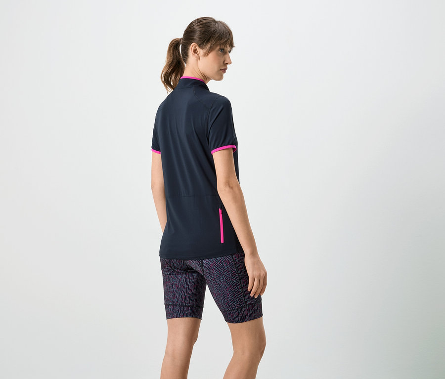 Femme vue de dos portant un t-shirt bleu marine à manches courtes avec des détails roses et un short à motifs.