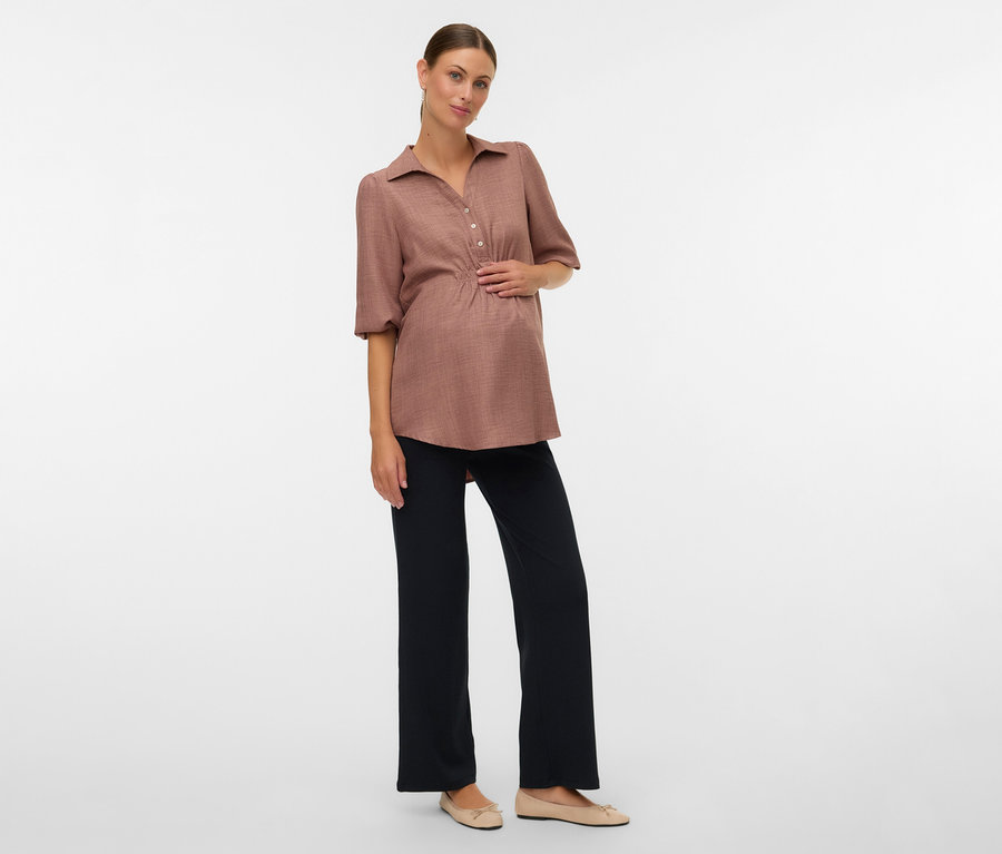 Femme enceinte avec chemisier marron et leggings décontractés MAMALICIOUS «
MLEMILY » posant sur fond blanc.