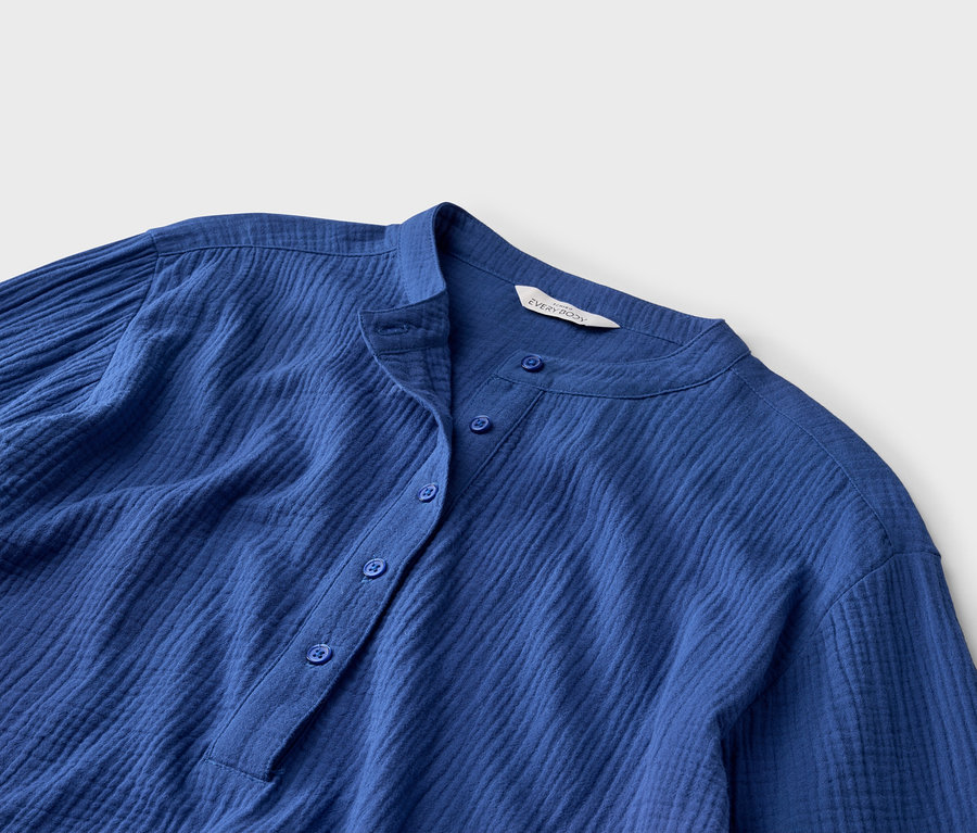 Gros plan d'une chemise bleue boutonnée avec un col montant et des manches longues.