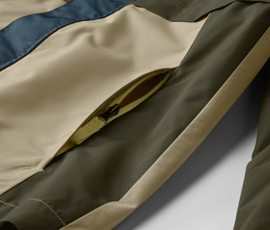 Gros plan d'une veste avec une poche zippée beige, vert olive et bleue.