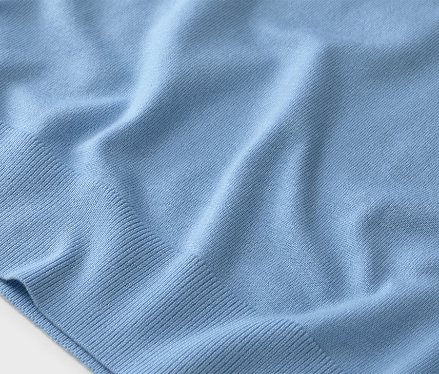 Gros plan d'un pull en tricot bleu clair avec des poignets côtelés.