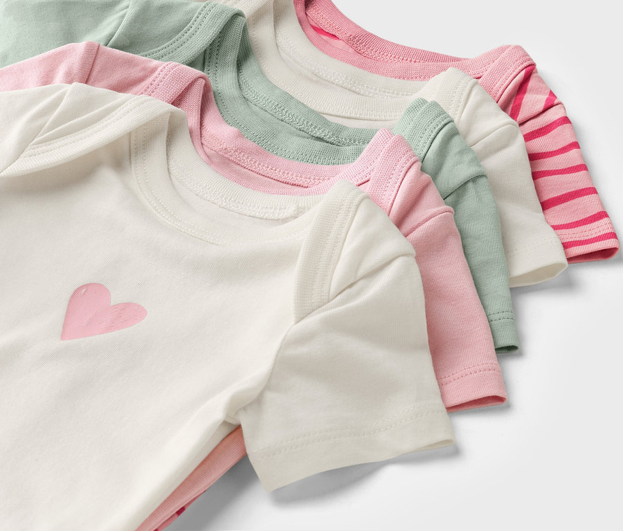 Des bodies de bébé à manches courtes multicolores sont empilés les uns sur les autres.