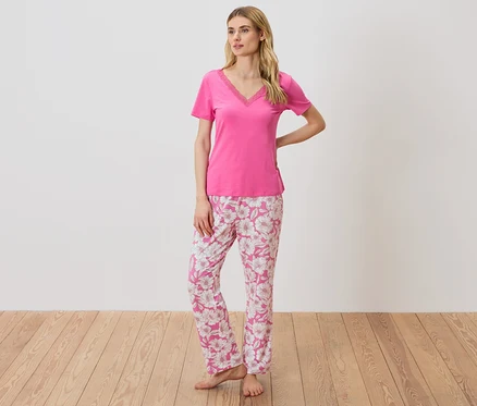 Femme portant un t-shirt rose avec détails en dentelle et un pantalon de pyjama à fleurs.