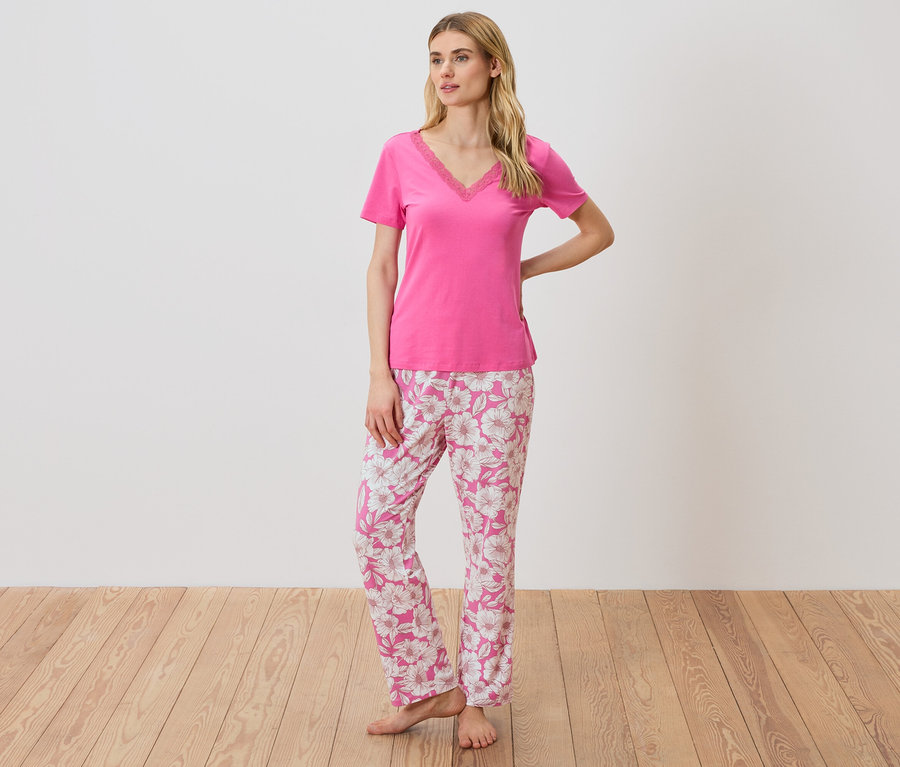 Femme portant un t-shirt rose avec détails en dentelle et un pantalon de pyjama à fleurs.