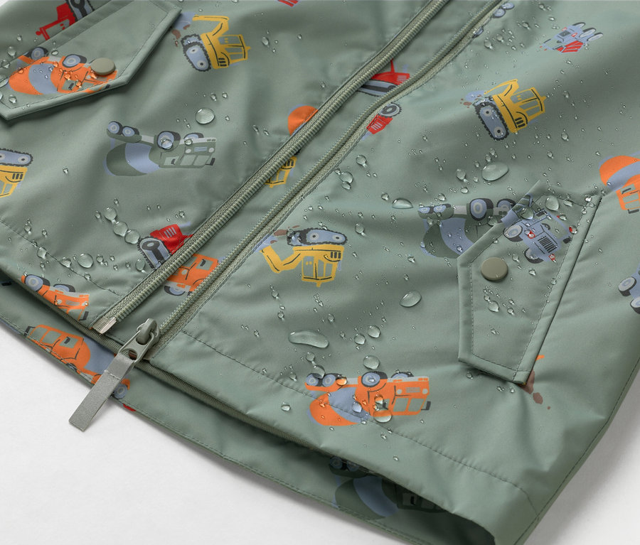 Gros plan d'une veste vert olive avec fermeture éclair et motif de chantier, recouverte de gouttes d'eau.