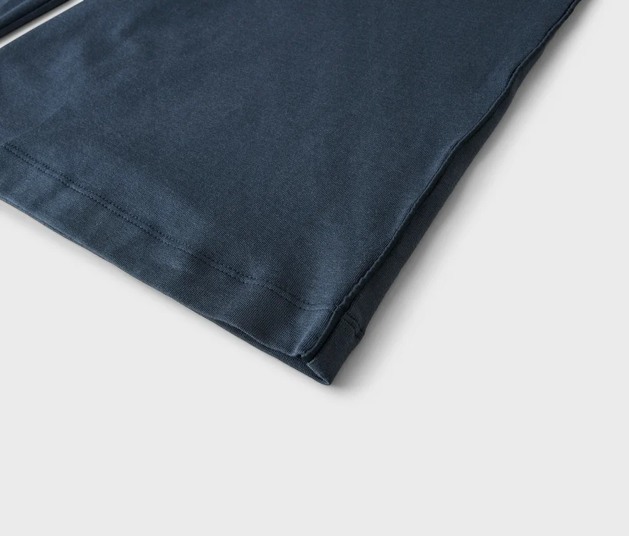 Gros plan d'un tissu bleu foncé, montrant l'ourlet avec des coutures visibles et une couture latérale.