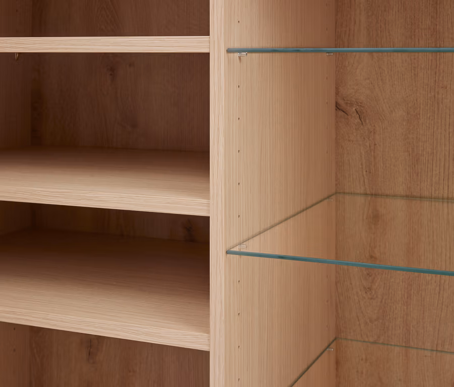Gros plan d'une armoire en bois clair avec deux étagères en bois à gauche et deux étagères en verre à droite.