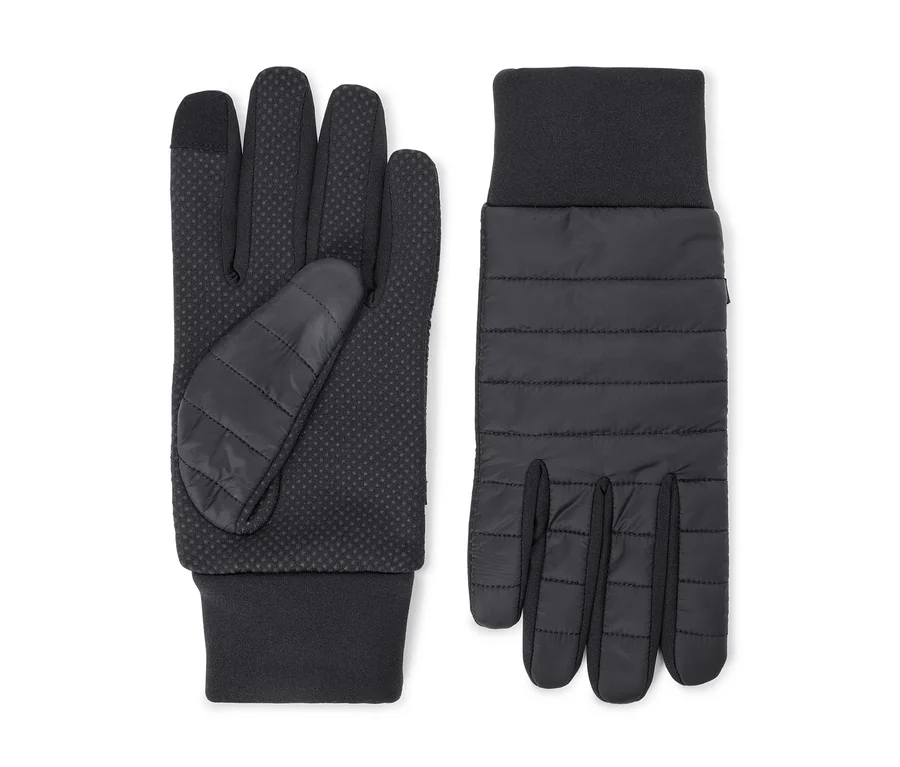 Une paire de gants noirs. Le gant gauche montre une paume à pois antidérapants et un pouce matelassé. Le gant droit montre un dos matelassé. Les deux ont des poignets côtelés.
