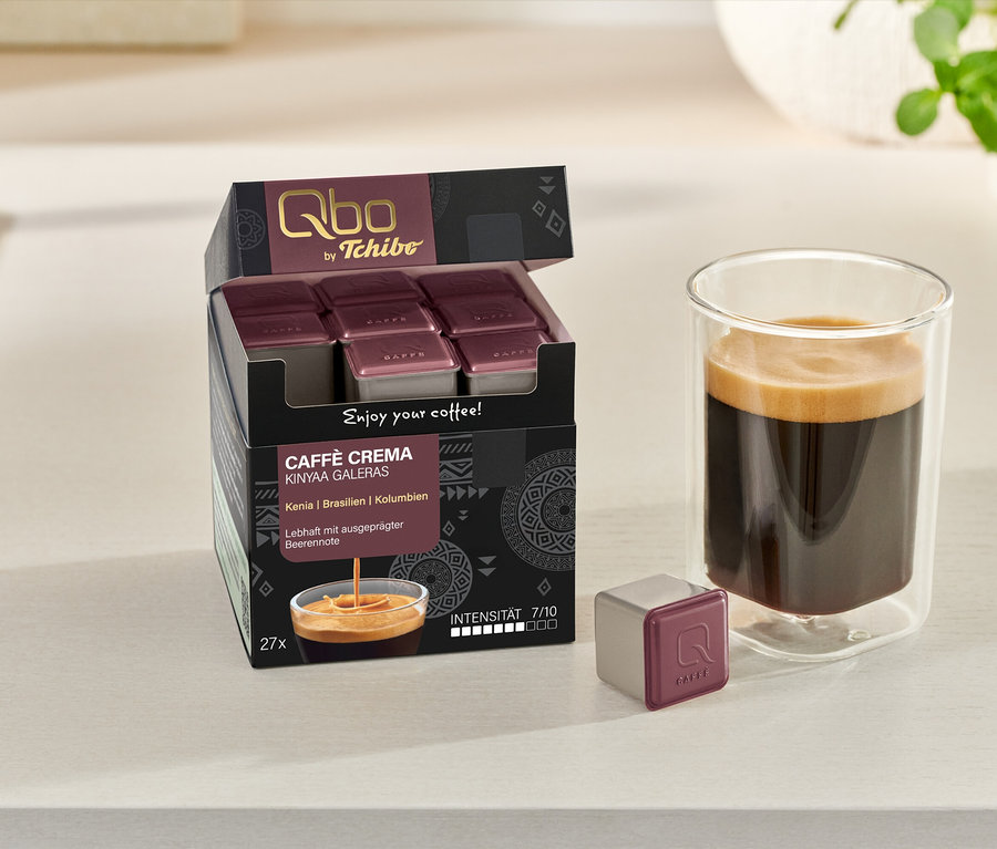 Boîte ouverte de Qbo Caffè KINYAA GALERAS avec tasse à café et capsule sur la table.