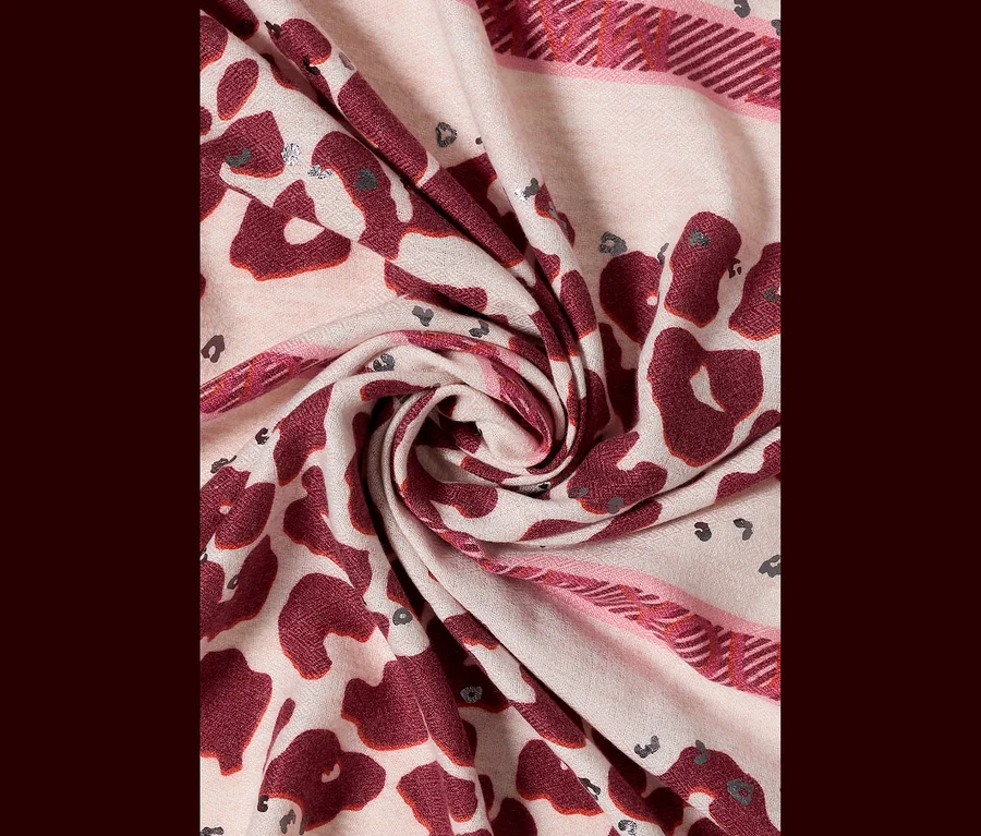 Gros plan d'un foulard triangulaire CECIL plié avec un motif léopard rose et bordeaux, accentué de détails argentés.