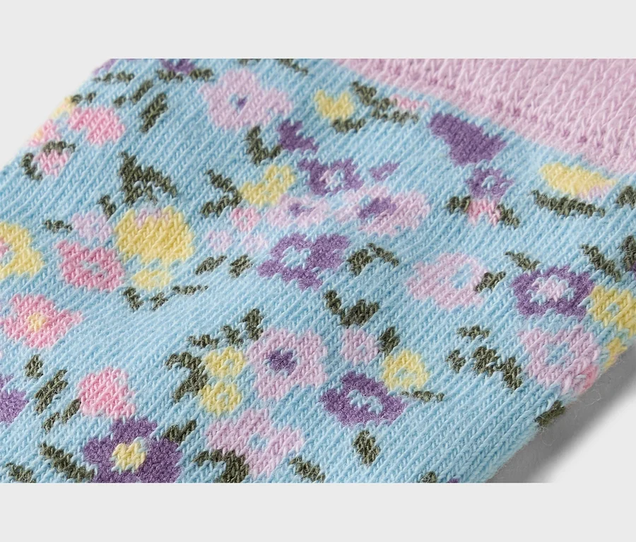 Gros plan d'une chaussette bleu clair avec un motif floral jaune, violet et rose.
